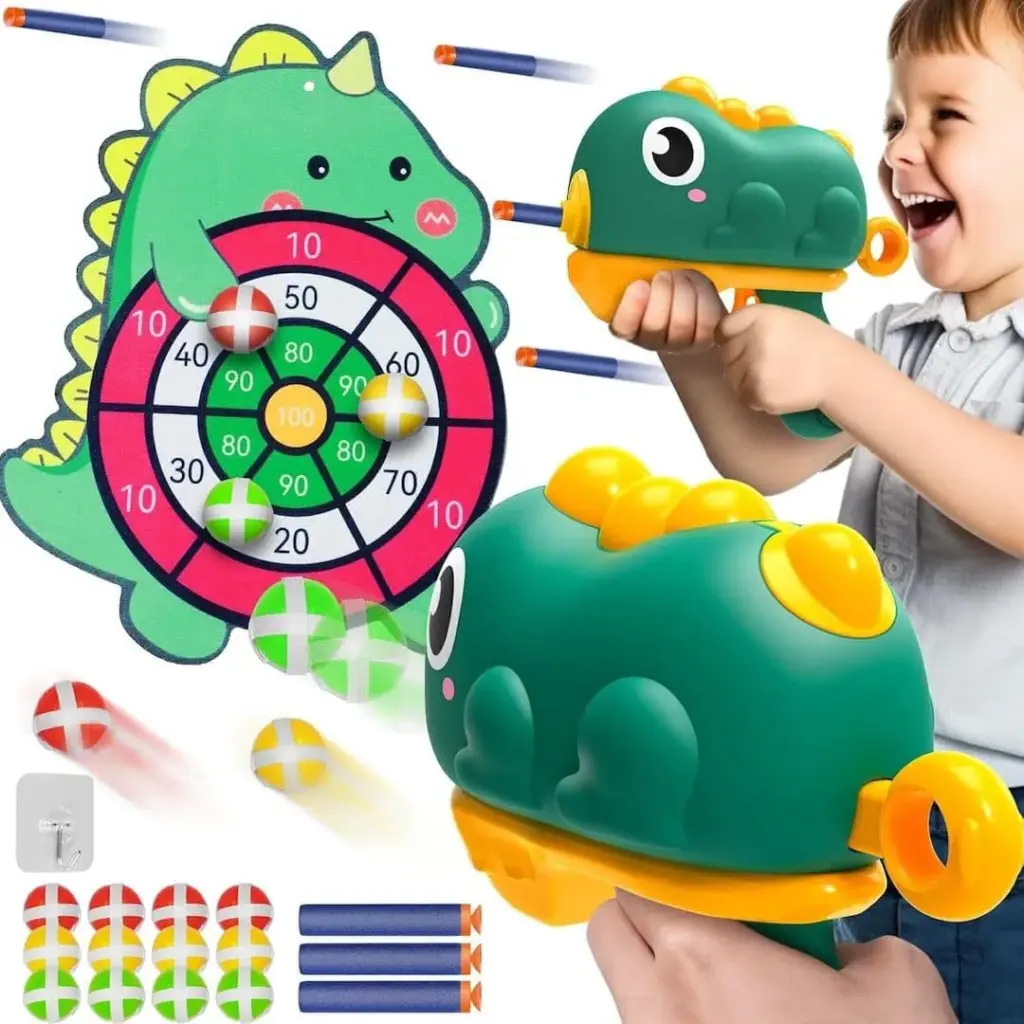 Otrok se veselo igra z Dino Strelec - Streljaj in Zadeni, zelenim dinozavrskim puskalnikom na temo dinozavra, ki meri na pisan pikado za pikado. Penasti puščice, majhen čep in črtaste žogice popestrijo to živahno in igrivo sceno, ki pooseblja mladostniško avanturo.
