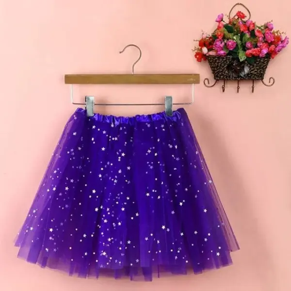 Vijolično tutu krilo, okrašeno z majhnimi belimi zvezdicami, visi na lesenem obešalniku ob nežno rožnati steni. Desno je okrasna košara z živahnimi cvetovi.